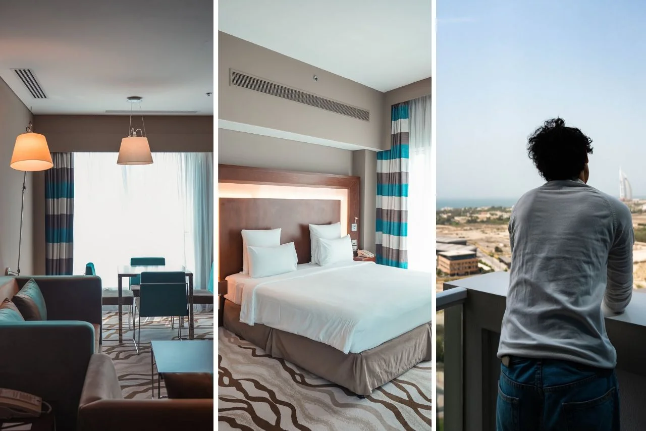 Stylish hotel room with modern decor, a cozy sitting area, elegant bed, and a person gazing out from the balcony, enjoying a picturesque city view.